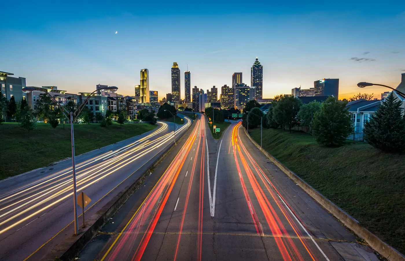 A highway interchange leading into a city skyline at dusk